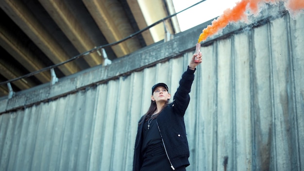 Girl protesting on street with smoke bomb in hand Woman holding smoke flare