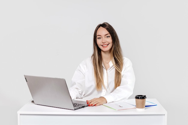 girl psychologist sitting at a table with a laptop smiling isolated on a white background