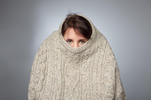 Girl pulls a large knitted sweater over her head Despair and loneliness of depressed person