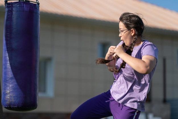 Girl punching sandbag. Muaythai boxing training. Healthy girl punching at boxing bag.