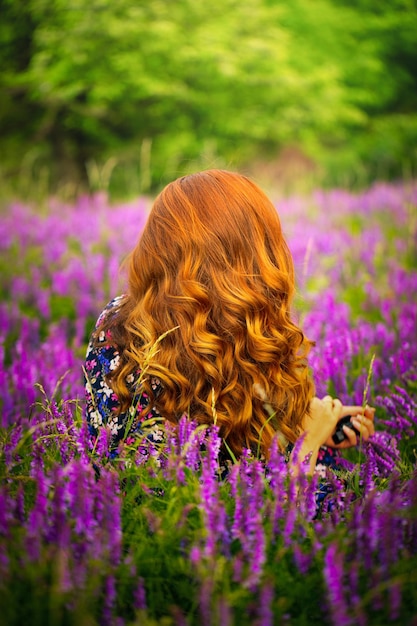 Una ragazza con un vestito viola su uno sfondo di fiori blu