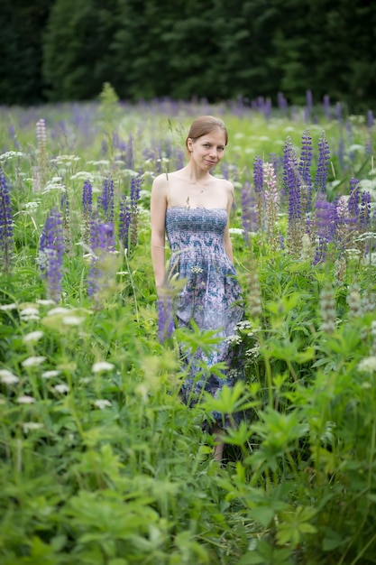A girl in a purple dress in a thicket of lupins