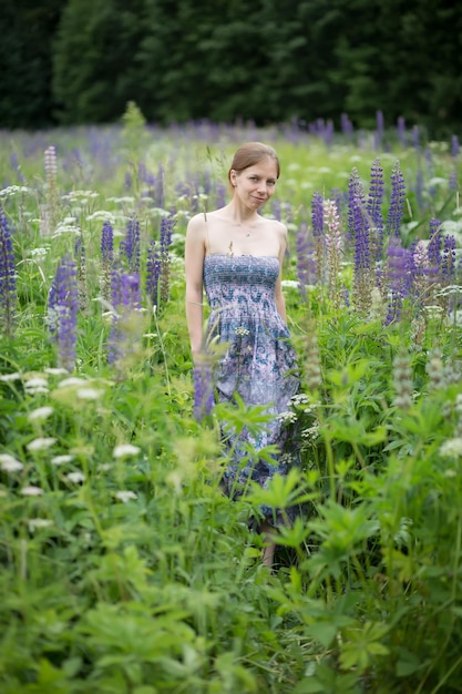 Foto una ragazza con un vestito viola in un boschetto di lupini