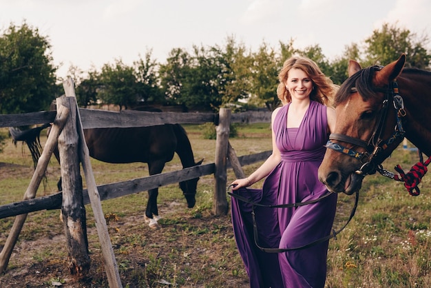 A girl in a purple dress on a walk with a horse.