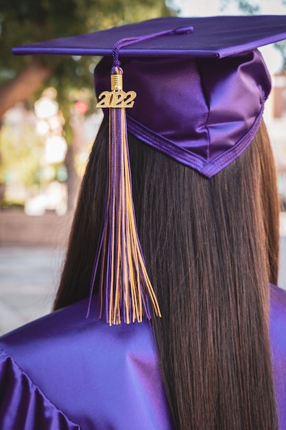 Foto la ragazza con l'abito viola da laurea da dietro.