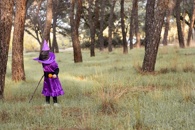 girl in a purple witch costume in a forest Halloween Autumn