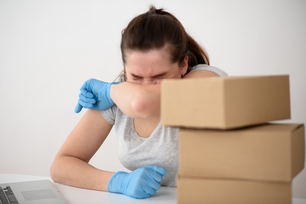 The girl pushes her elbow in gloves at the table with corton boxes in the foreground