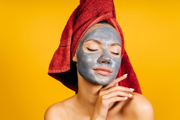 The girl put a coal mask on her face and closed her eyes enjoying the process. background yellow