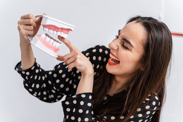 Girl put finger to a dental educational jaw. Plastic jaw bites a girl by a finger. Funny emotions.