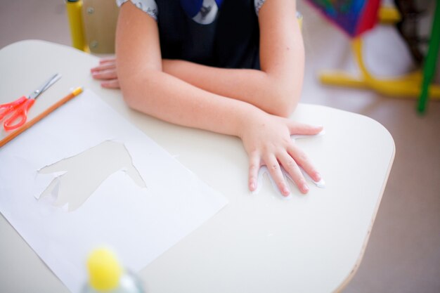 The girl put her hand on the paper cut out hand