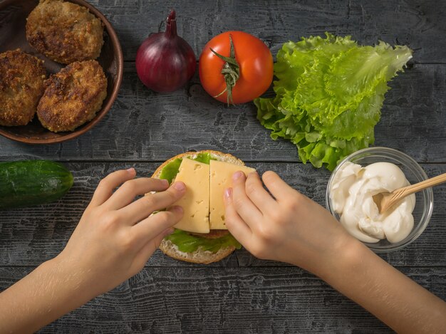 The girl puts the cheese in the manufacture of hamburger