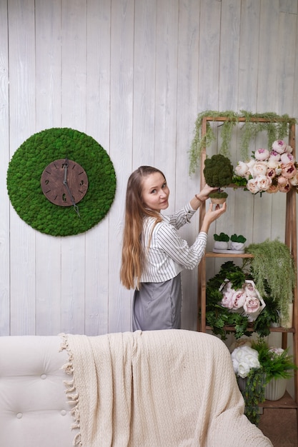 The girl puts flowers on the shelf