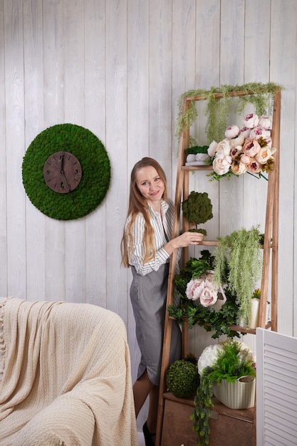 The girl puts flowers on the shelf