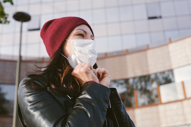 Photo the girl puts on a medical mask on her face. against the background of a glass business center.