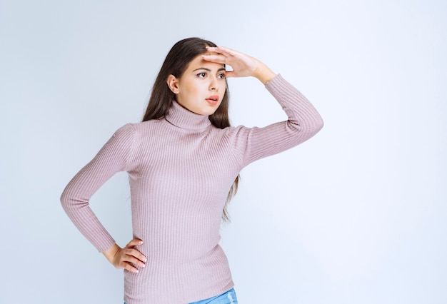 Girl putting hand to her forehead and looking for someone. 