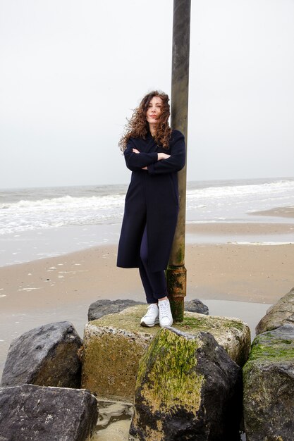 Photo girl rain sea wind winter portrait woman smile spring coat long hair curly mood shore snow beach autumn deadpan