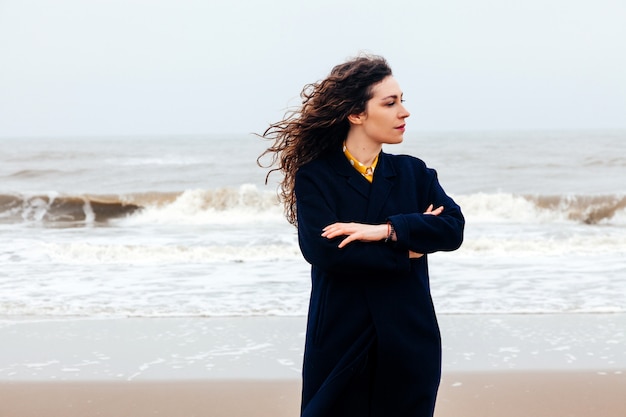 Girl rain sea wind winter portrait woman smile spring coat long hair curly mood shore snow beach