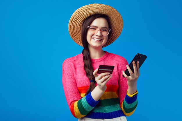 Girl in rainbow sweater holding plastic credit card and mobile phone