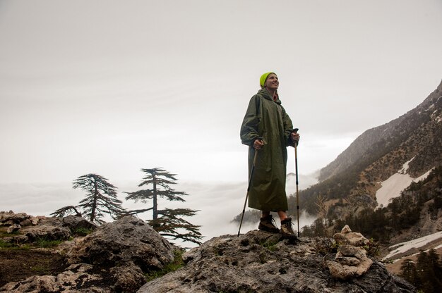Girl in the raincoat standing with hiking sticks