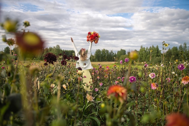 The girl raised her hands with a bouquet up in the field