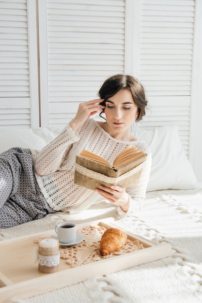 朝食を食べながら本を読んでいる女の子