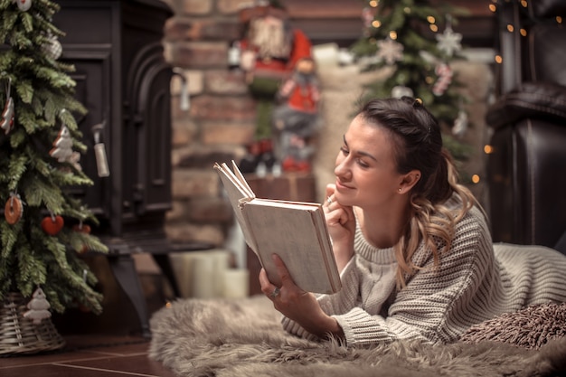 girl reading a book in a cozy home atmosphere near the fireplace