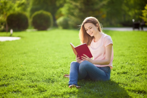 Girl reading book sitting on grass