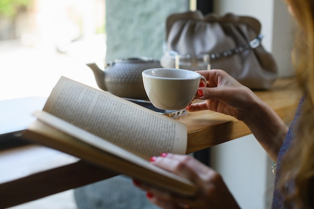 コーヒー ショップで朝食をとりながら本を読んでいる女の子