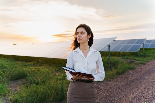 Girl reading near solar panel rows on the ground