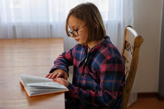 Photo a girl reads a book at the table