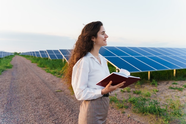 Girl reads near solar panel rows on the ground