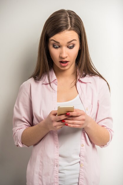 La ragazza legge qualcosa di sorprendente sul suo telefono.