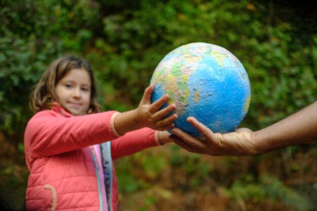 Photo girl receiving a globe from an adult while looking at the camera.