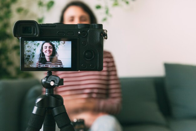 Ragazza che si registra con una telecamera a casa. messa a fuoco selettiva sulla fotocamera. concetto di videoblog