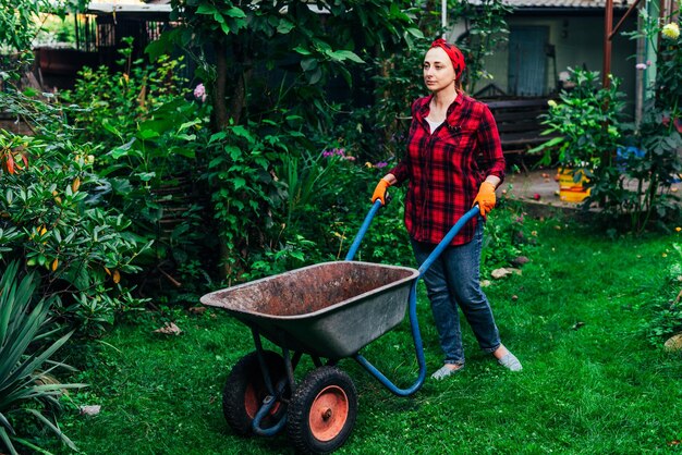 A girl in a red bandana and shirt is harvesting in the garden and vegetable garden