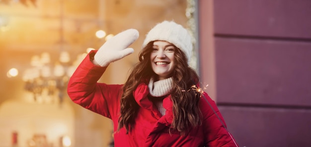 Foto ragazza con un cappotto rosso che tiene le luci del bengala c