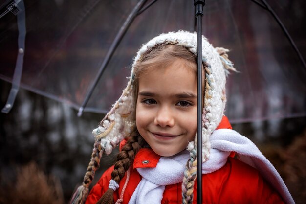 girl in red coat with transparent umbrella walking alone in spring forest