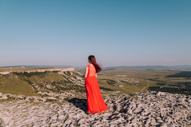 山のライフスタイルを背景に赤いドレスを着た女の子