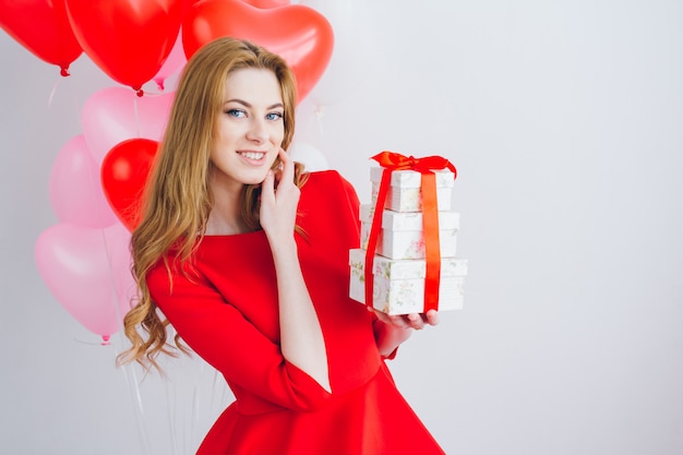 Girl in red dress holds boxes with gifts