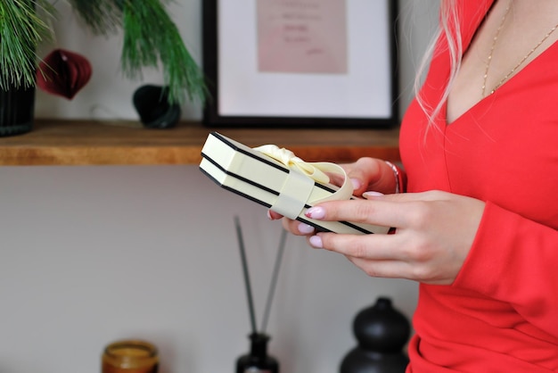 A girl in a red dress holds a gift in her hands Closeup