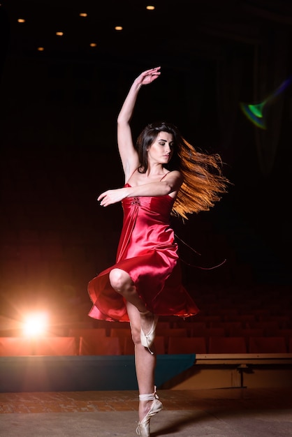 Una ragazza in un vestito rosso sta ballando sul palco.