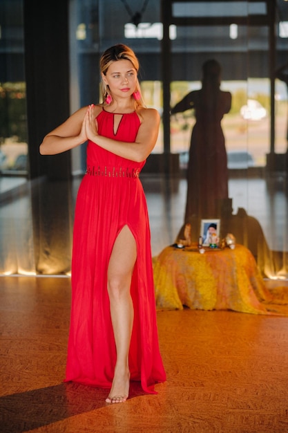 A girl in a red dress moves in a dance meditating indoors Dynamic dance