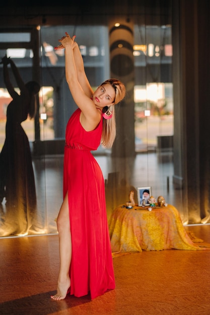 A girl in a red dress moves in a dance meditating indoors  dynamic dance