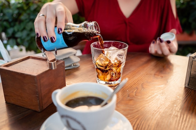 Foto ragazza in abito rosso versa una bevanda cola caffè ghiaccio