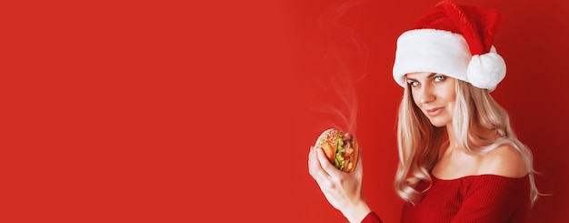 Girl in red dress and santa hat with burger in hands