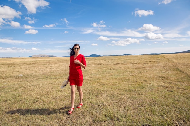 girl in red dress standing in a field in autumn