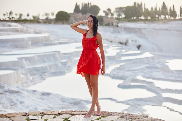 Girl in red dress on white travertines, Pamukkale