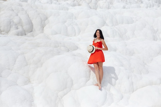 Girl in red dress on white travertines, Pamukkale