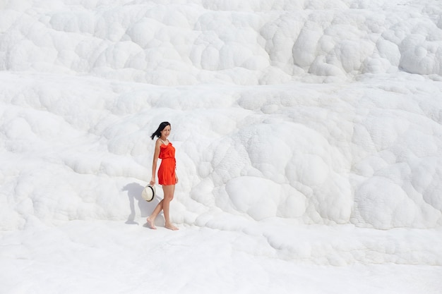 Girl in red dress on white travertines