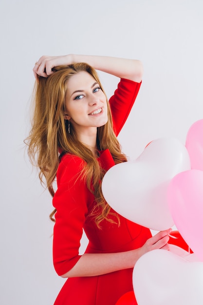 Girl in red dress with balloons in the shape of a heart